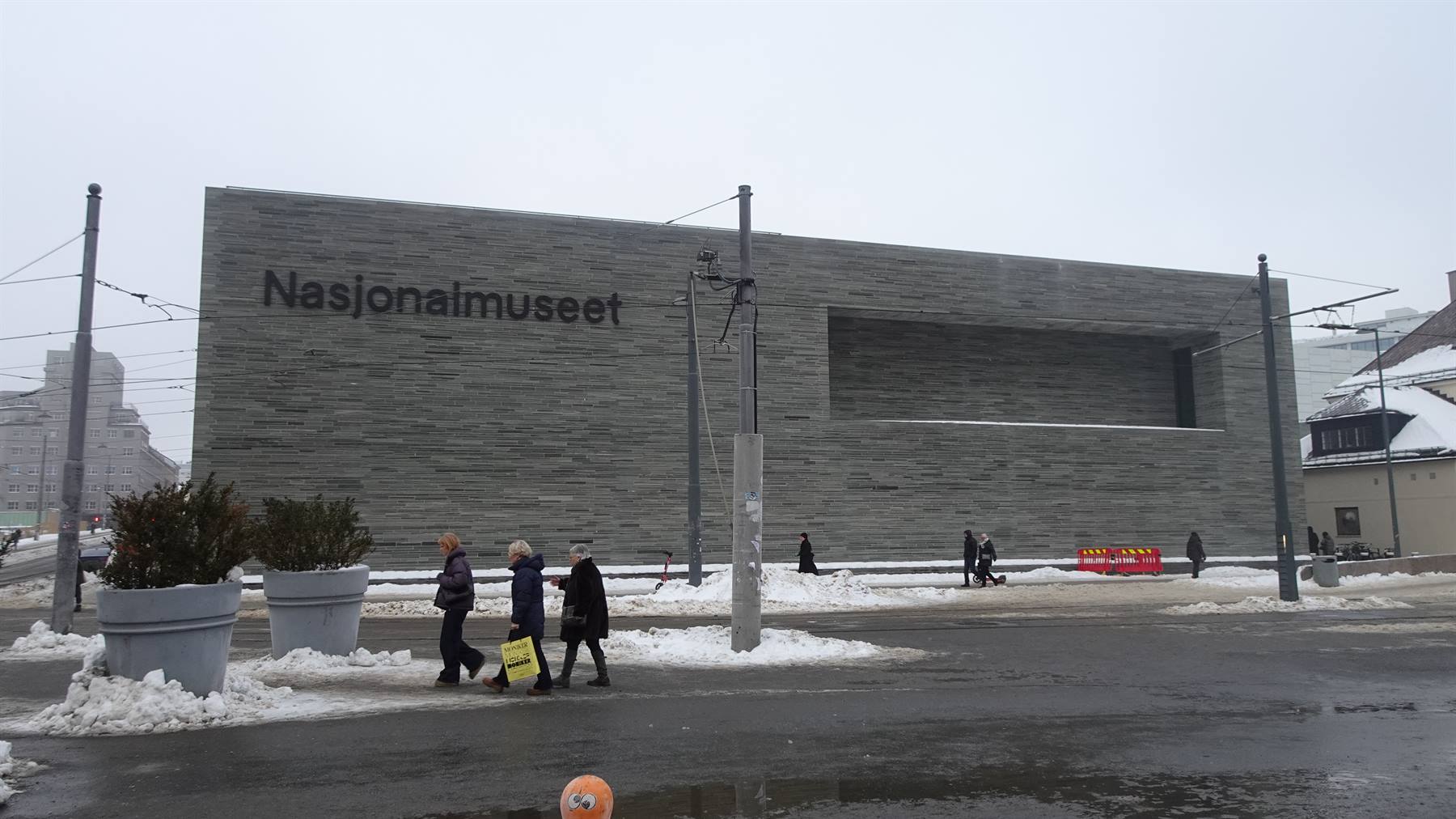 Turisti camminano sulla neve davanti alla facciata grigia del Nasjonalmuseet