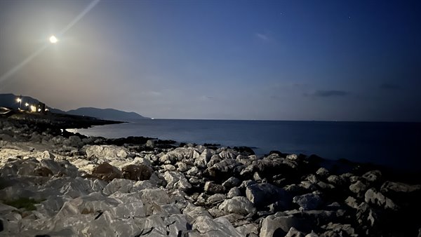 The moon caresses the white stones and the sea is silent, enchanted.