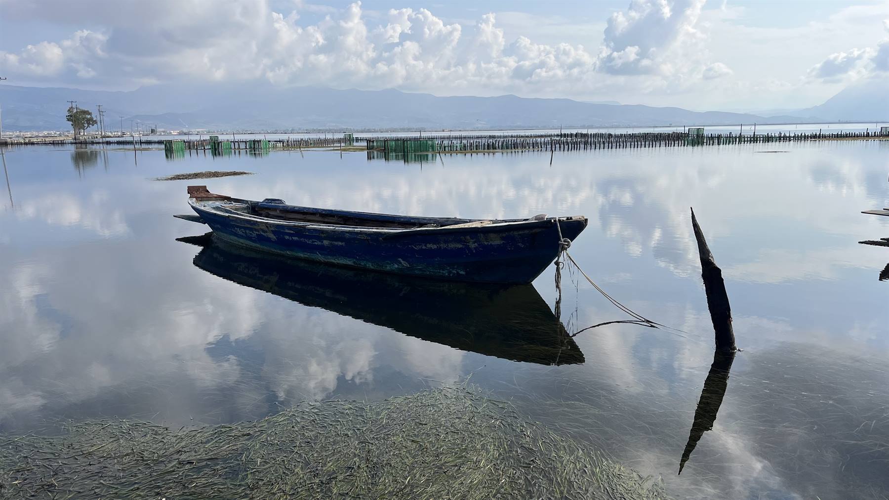 La barca dondola silenziosa, il cielo specchiato nell'acqua calma.