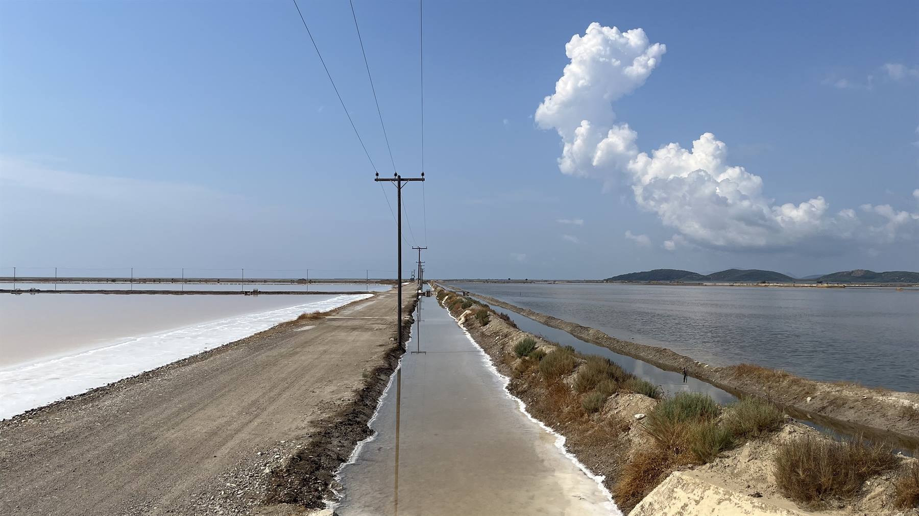 Cammino tra le saline, il cielo si specchia nell'acqua salata.