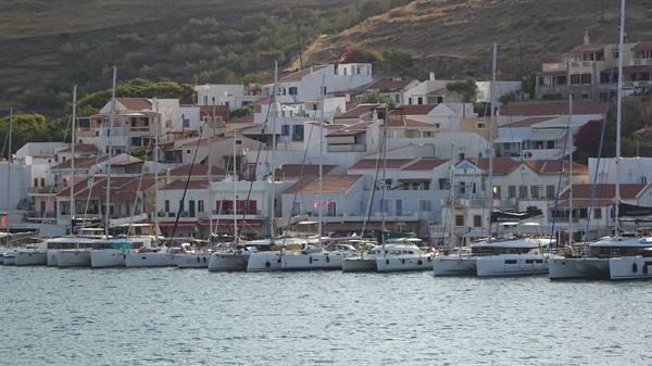 Sails still in the harbour, white houses embracing the bay at sunset.