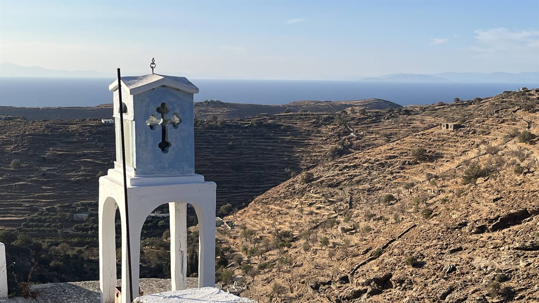 Un piccolo campanile bianco custodisce il silenzio davanti al mare Egeo.