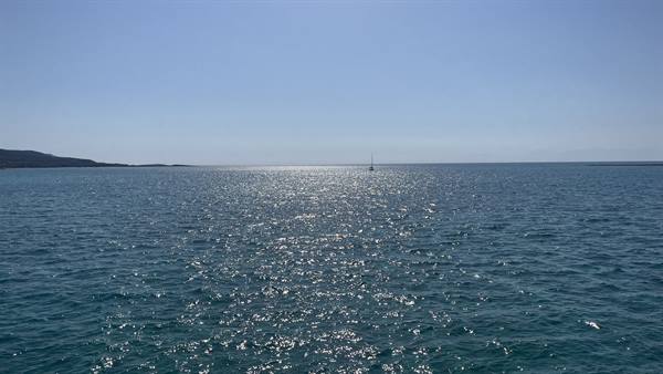 The sea sparkles with gold and a lonely shadow sails the horizon.