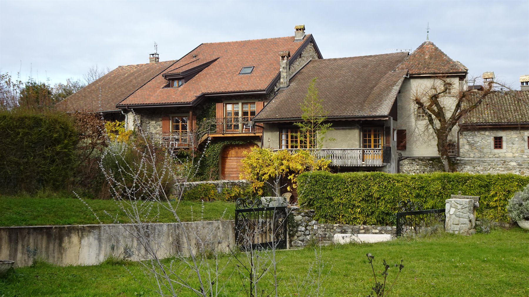 Case in pietra e legno con tetti di tegole a Yvoire, tra siepi verdi e prato