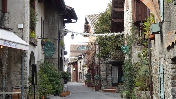 Stone alley with restaurant signs and garlands, Yvoire