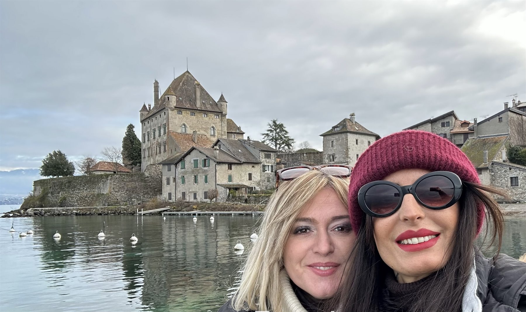 Selfie davanti al castello di Yvoire sul lago, case in pietra e cielo grigio
