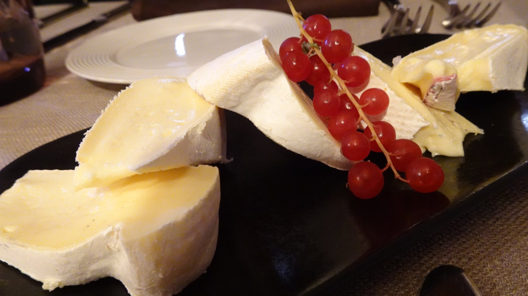 Tavola ad Annecy: formaggio bianco e ribes rossi su piatto nero