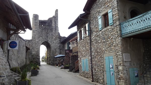 Ancient stone gate and houses with turquoise shutters in Yvoire village