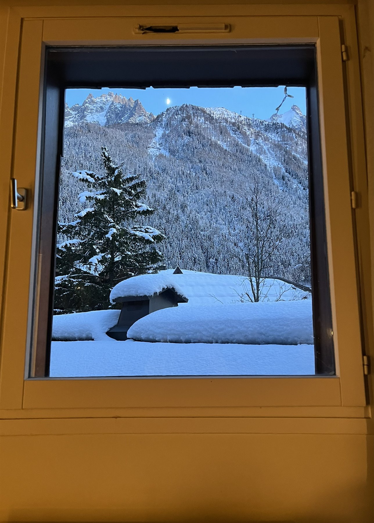Dalla finestra innevata di Chamonix, la luna sopra le vette alpine