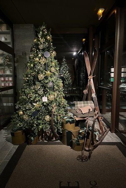 Decorated Christmas tree with gifts and vintage skis at a Chamonix hotel entrance