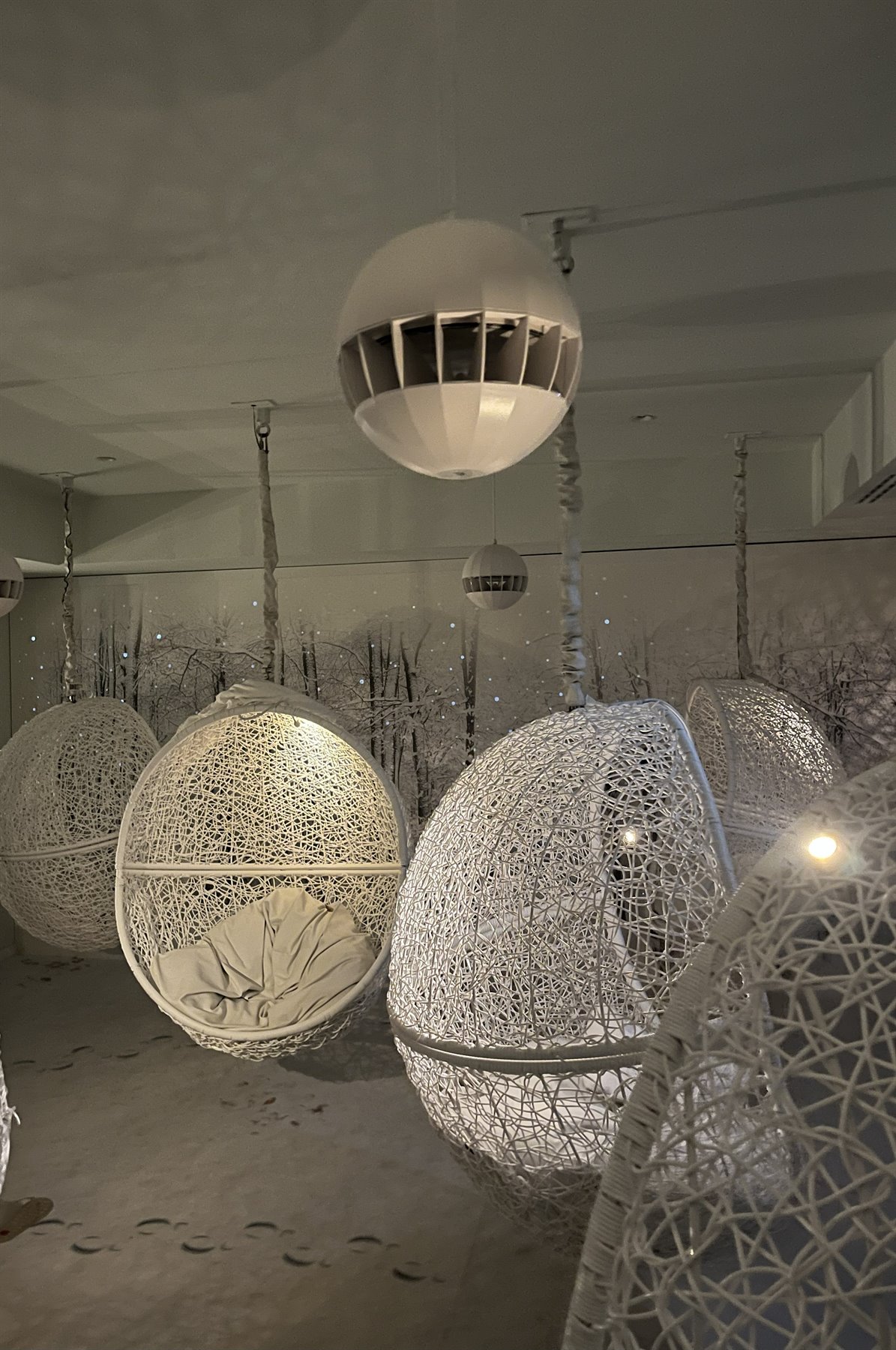Poltrone sospese intrecciate bianche in una sala dimessa con luce calda