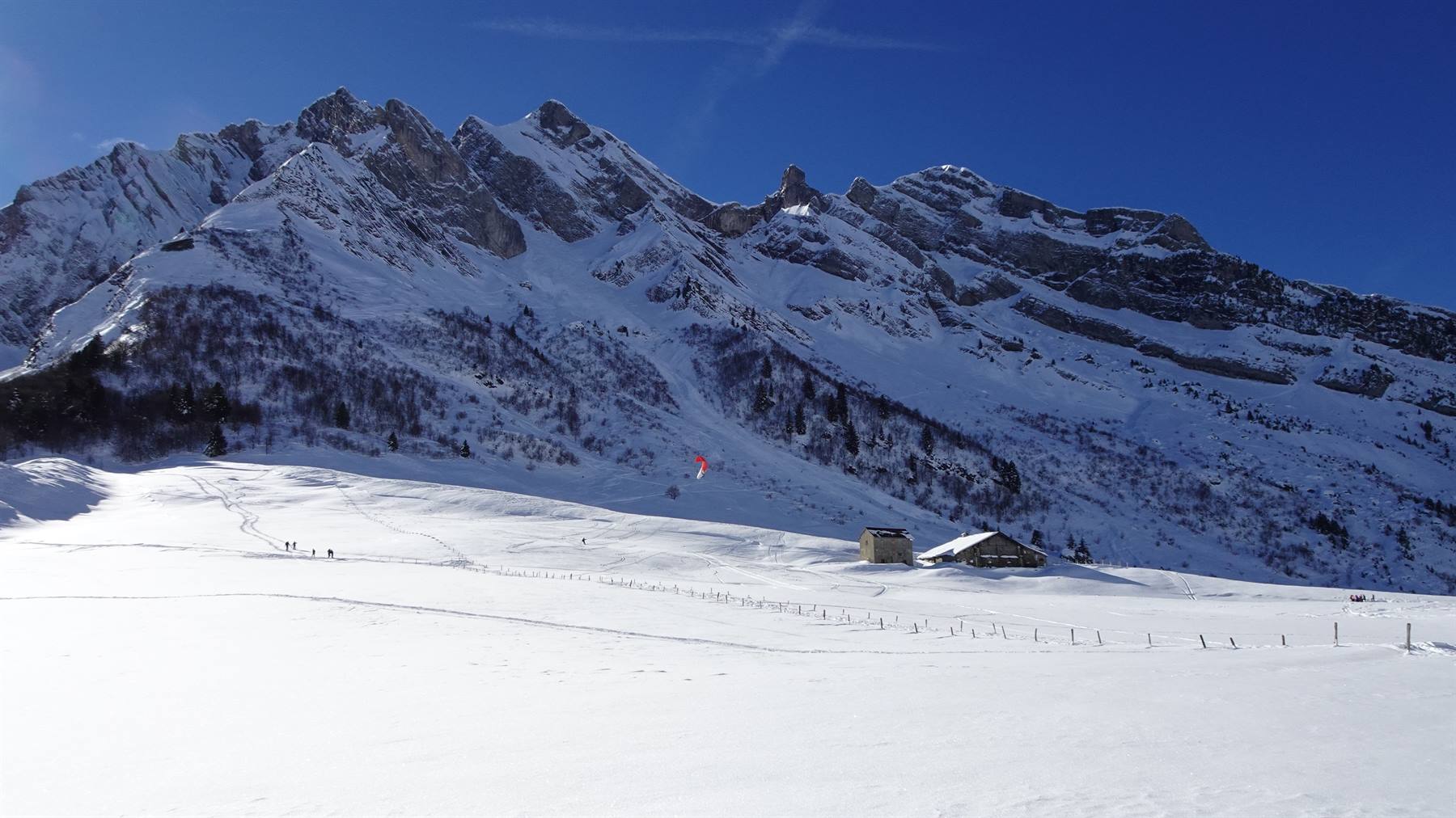 Baite in legno su neve sotto le vette rocciose del Col des Aravis