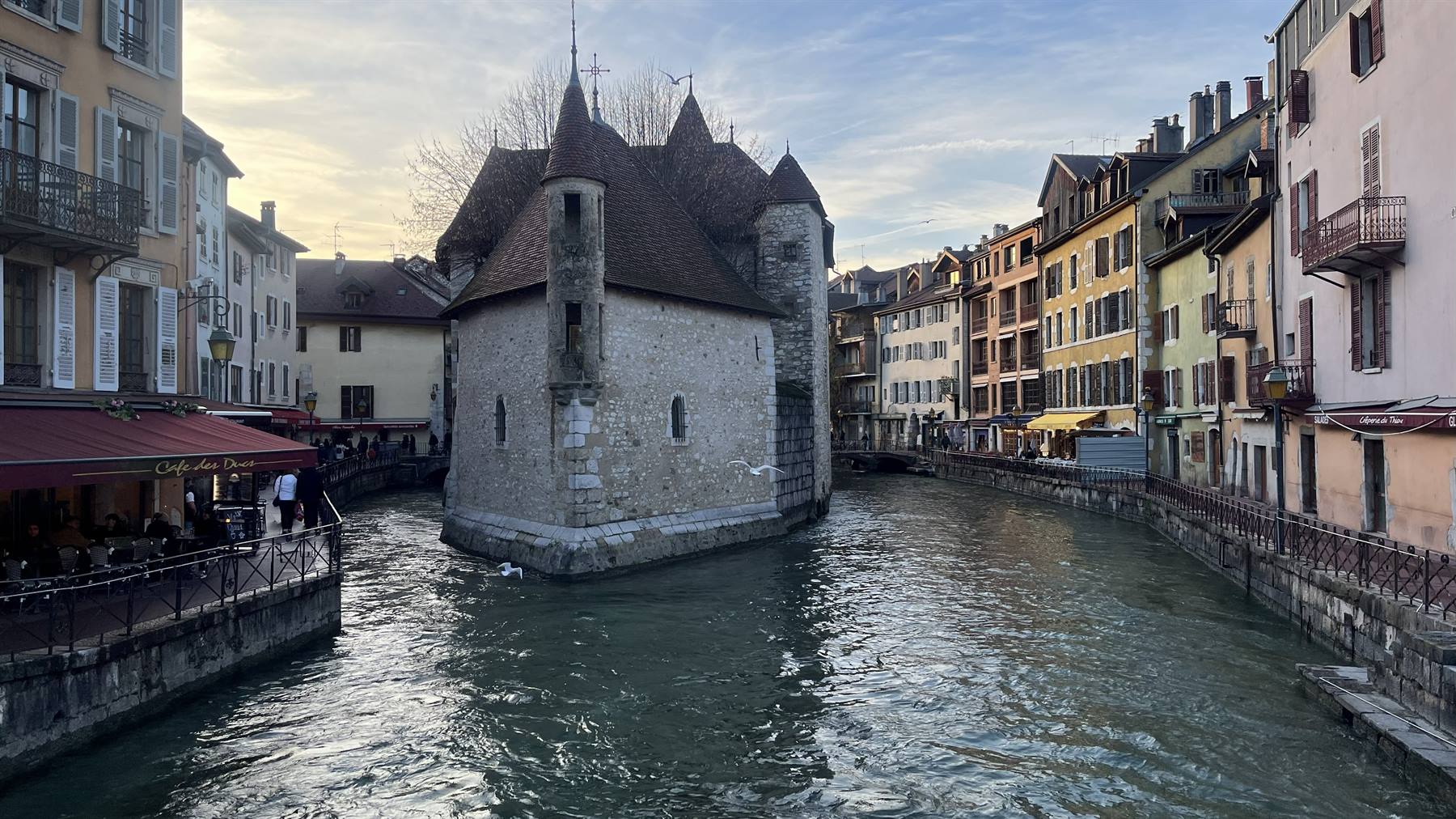 Il Palais de l'Isle su canale, Annecy, luci serali sui caffè
