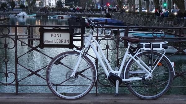 White bike on Pont Albert Lebrun, canal with boats in Annecy