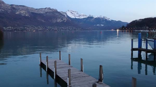Wooden jetty on Lake Annecy, snow-capped mountains at dawn