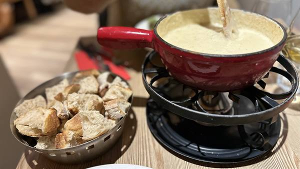 Cheese fondue in red pot with bread cubes, restaurant in Yvoire