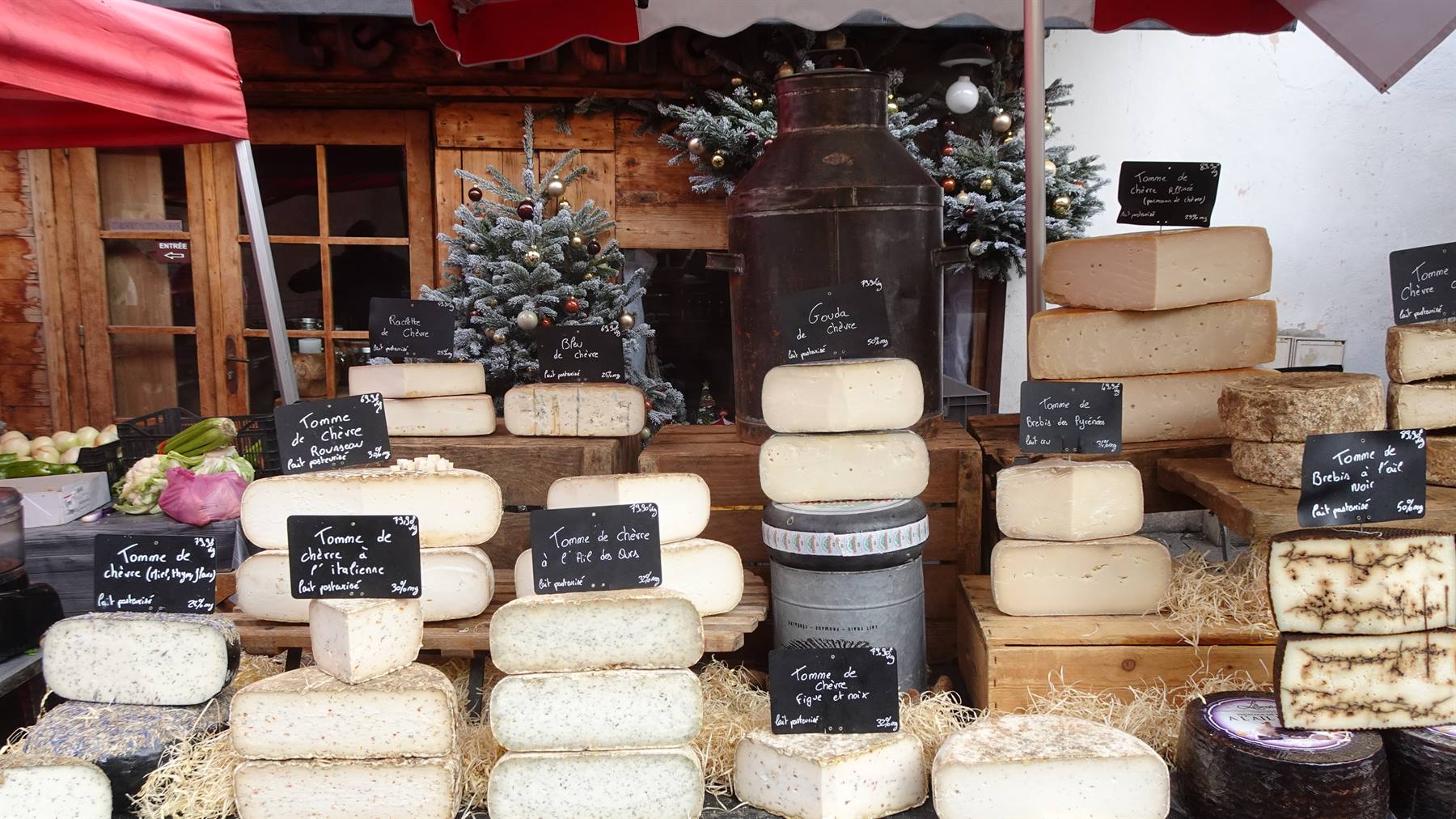 Banco di formaggi di montagna in un mercato di Yvoire, lavagne con prezzi