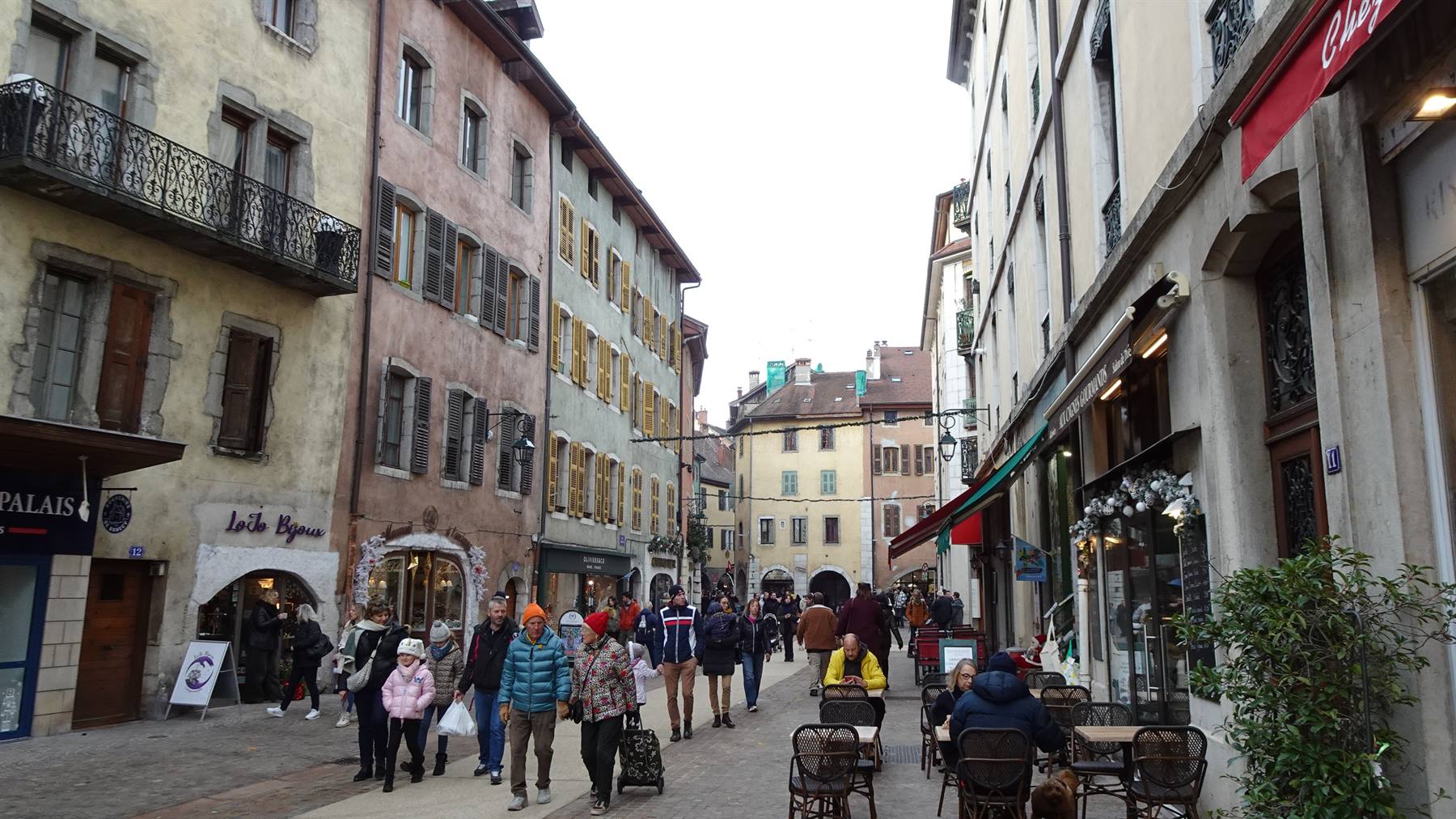 Pedoni in una via pedonale di Annecy tra facciate antiche e caffè