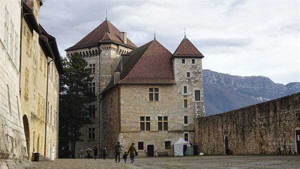 Annecy castle stone towers and slate roofs, visitors walking in the courtyard