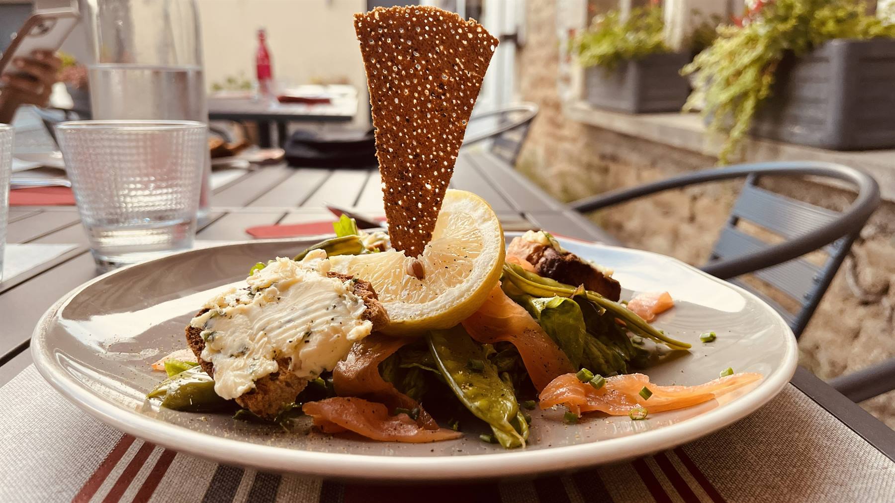 Piatto di insalata con salmone affumicato e pane croccante su terrazza all'aperto