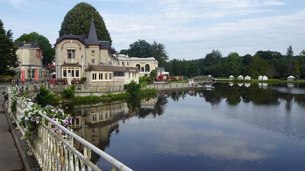 Turreted villa by Bagnoles de l'Orne lake, reflections and flowered railing