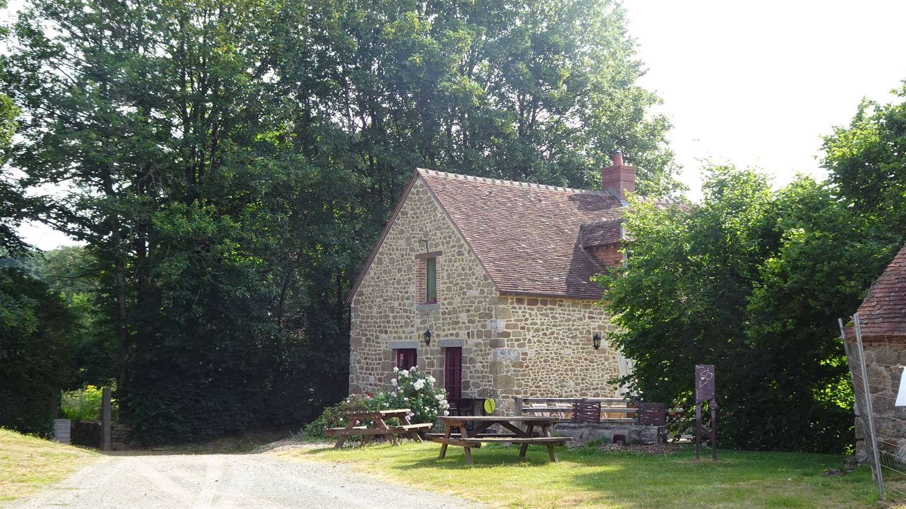 Casa in pietra con tavoli da picnic tra gli alberi, Saint Ceneri le Gerai
