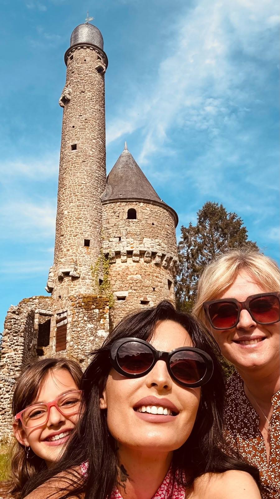 Tre donne sorridenti davanti alla torre in pietra dell'abbazia di La Lucerne