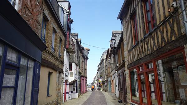 Cobbled street with timber-framed and stone houses, morning light in Domfront