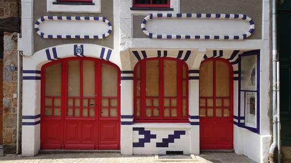 White, blue and red painted facade with arched doors and windows