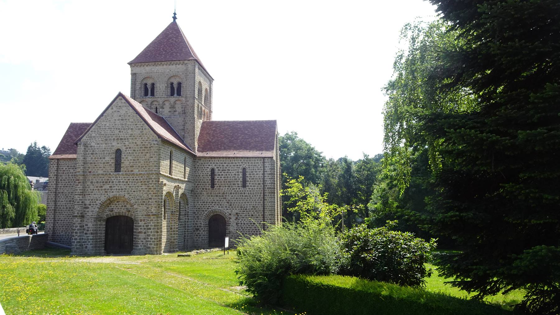 Chiesa romanica in pietra con campanile tra alberi a Saint-Céneri-le-Gérei