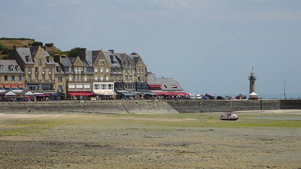 Cancale, boat stranded on sand at low tide, stone houses along the seawall