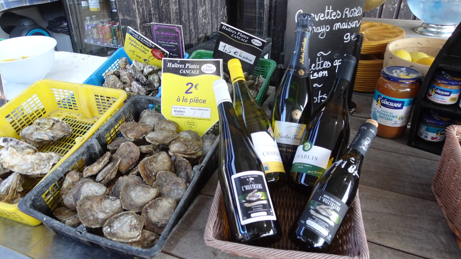 Ostrute fresche in cassette e bottiglie di vino bianco al mercato di Cancale