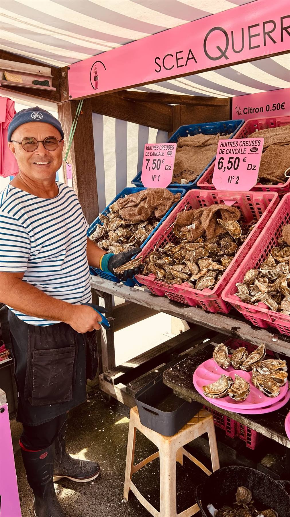 Venditore sorridente con ostriche di Cancale in casse rosa al mercato