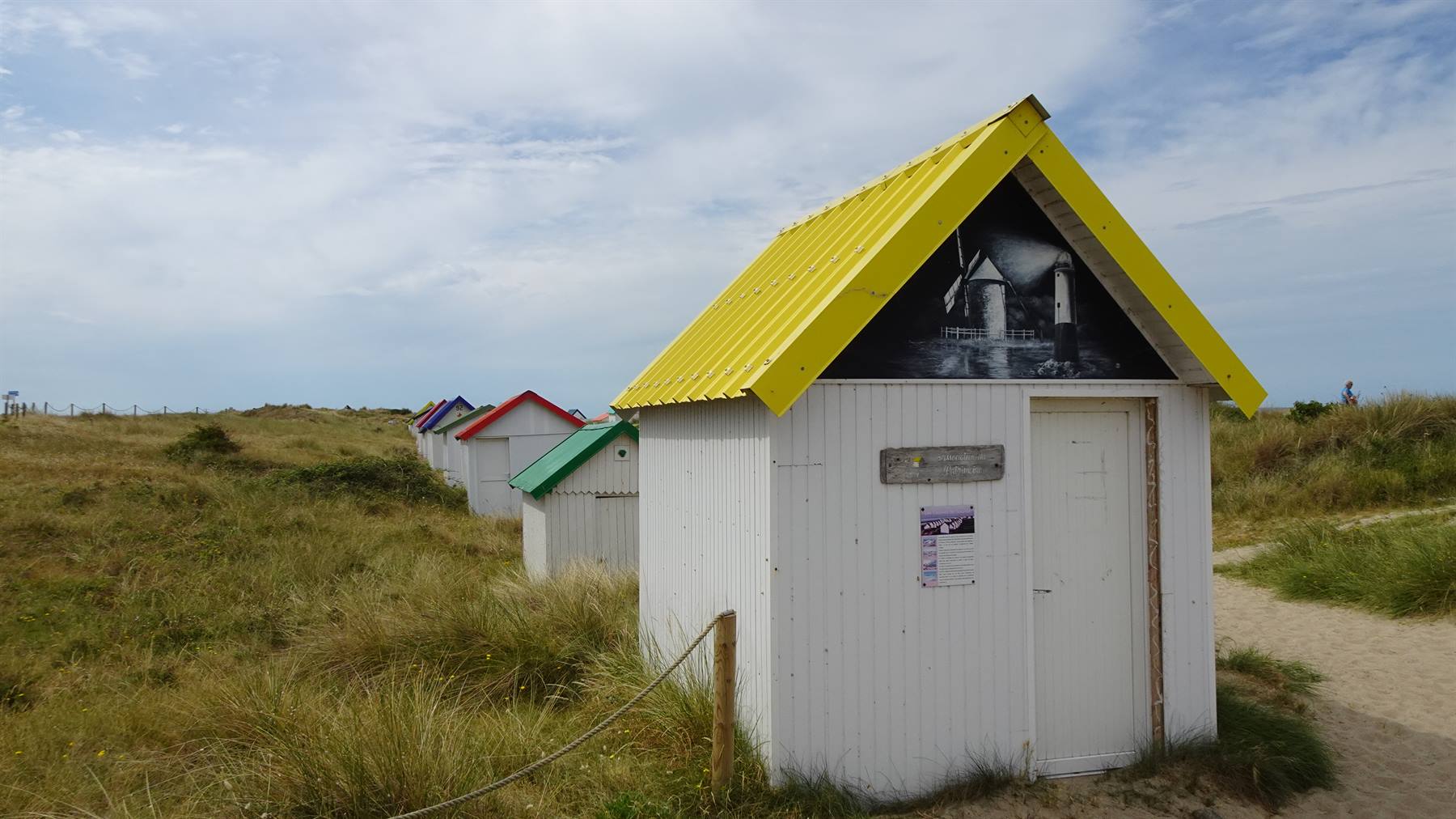 Cabine da spiaggia colorate tra le dune erbose di Gouville sur Mer