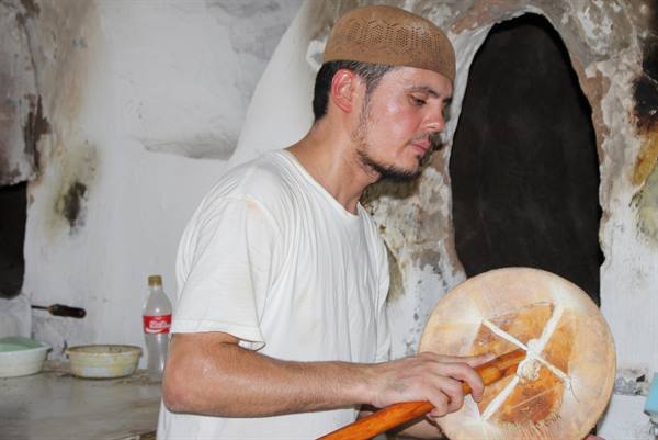 Fornaio stampla il pane con un timbro davanti al forno tradizionale