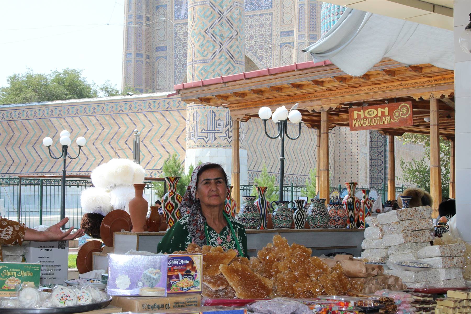 Venditrice di dolci e ceramiche davanti al Registan di Samarcanda
