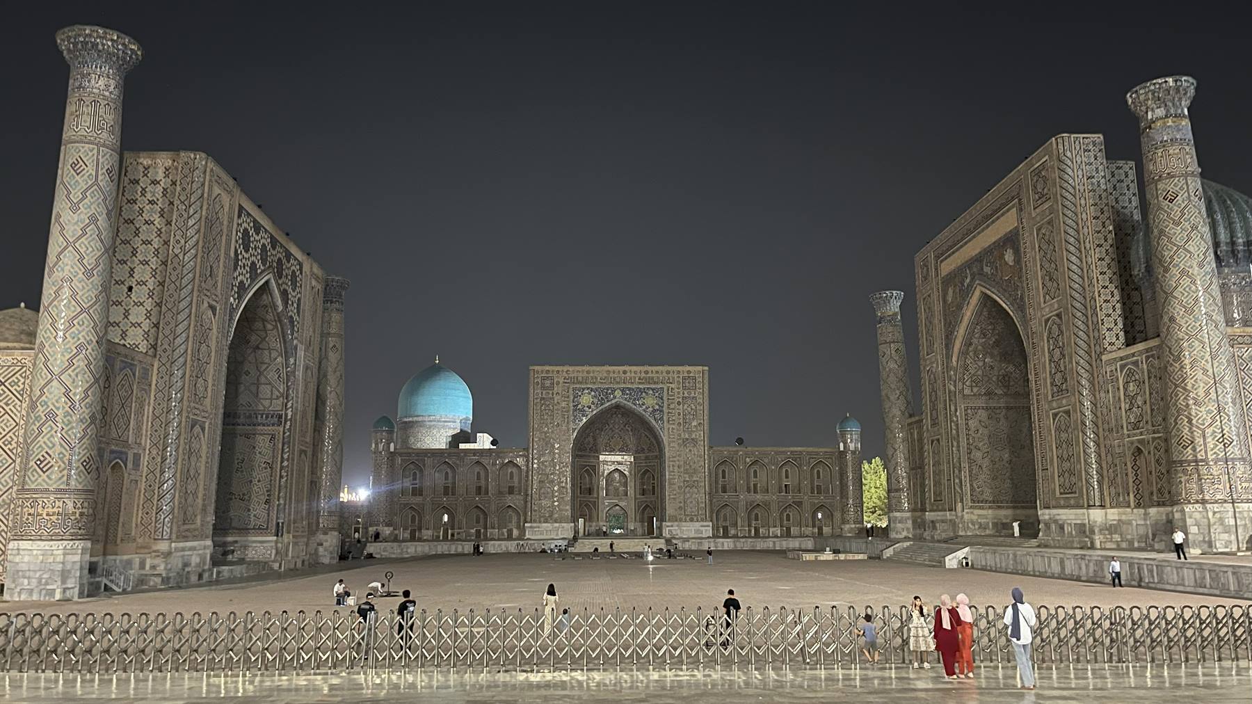 Piazza Registan di Samarcanda illuminata di notte tra madrase e minareti