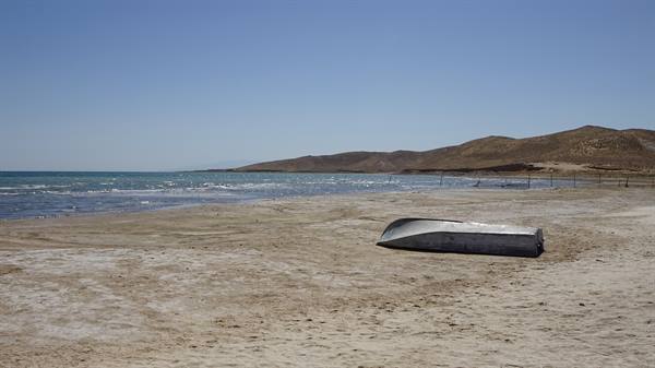 Barca di metallo rovesciata sulla spiaggia salata di Aydar Lake