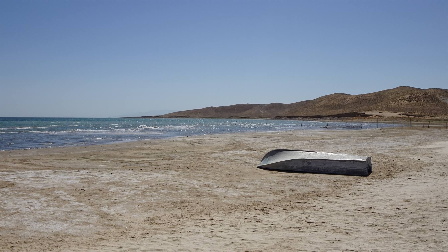 Barca di metallo rovesciata sulla spiaggia salata di Aydar Lake