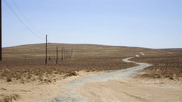 Strada sterrata tra le dune del deserto Kizilkum, piloni electricity… meglio: Pali della luce lungo 