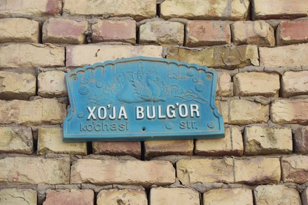 Targa via azzurra "Xo'ja Bulg'or" su muro di mattoni antichi