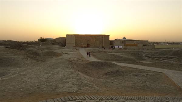 Rovine in mattoni di terra al sole basso, due turisti sul sentiero sabbioso