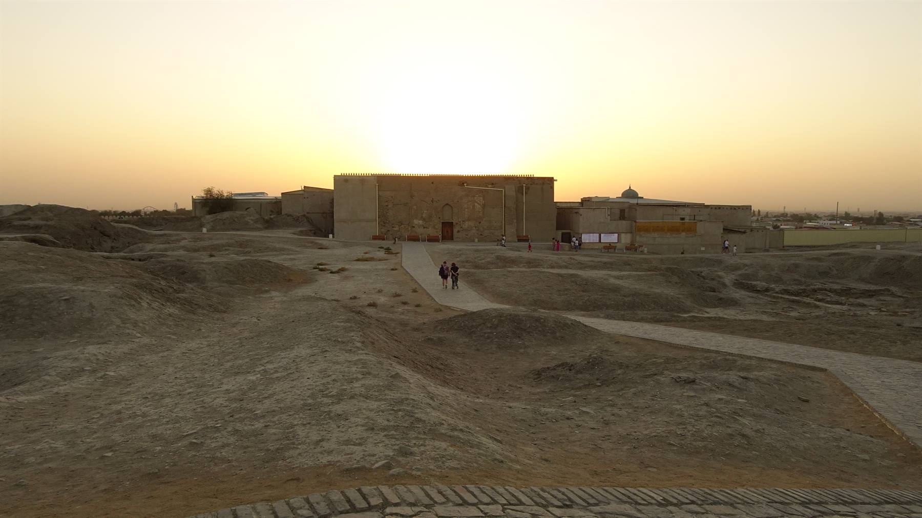 Rovine in mattoni di terra al sole basso, due turisti sul sentiero sabbioso