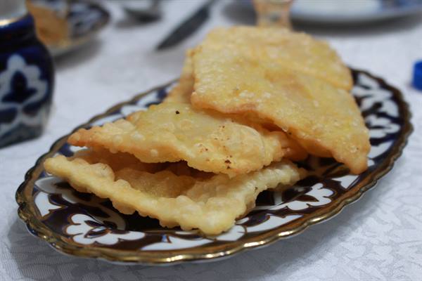 Frittelle dorate su piatto decorato in ceramica, tavola imbandita