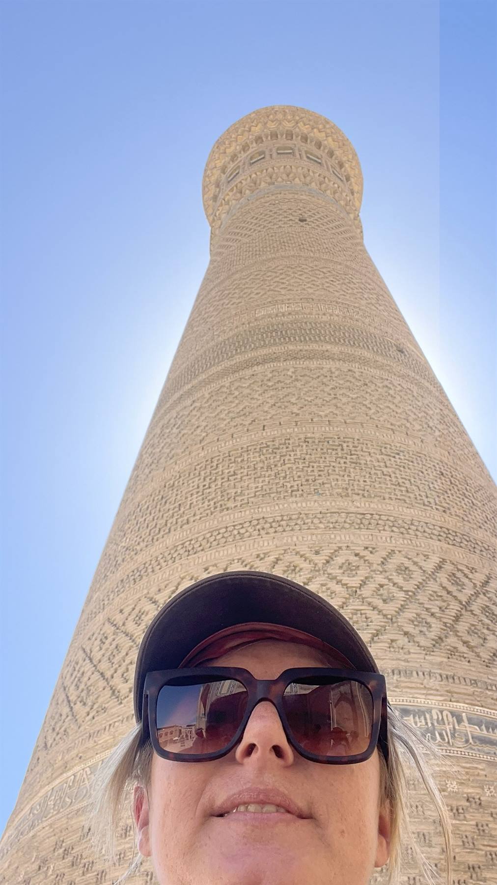 Selfie davanti al minareto Kalon, mattoni decorati sotto il cielo azzurro