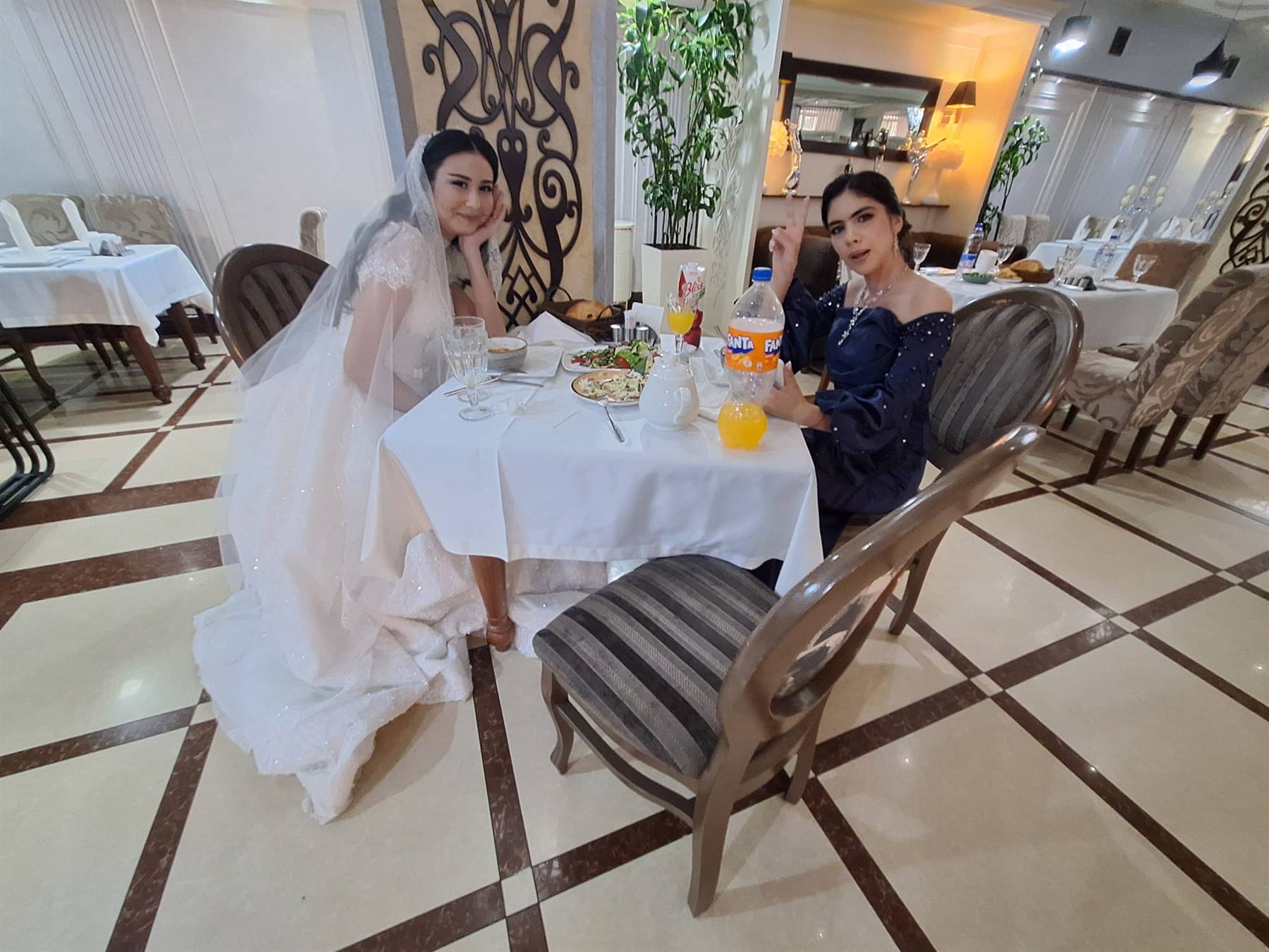 Sposa in bianco e amica a tavola in un ristorante di Tashkent