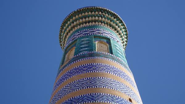 Il minareto di Khiva con maioliche blu e verdi contro il cielo
