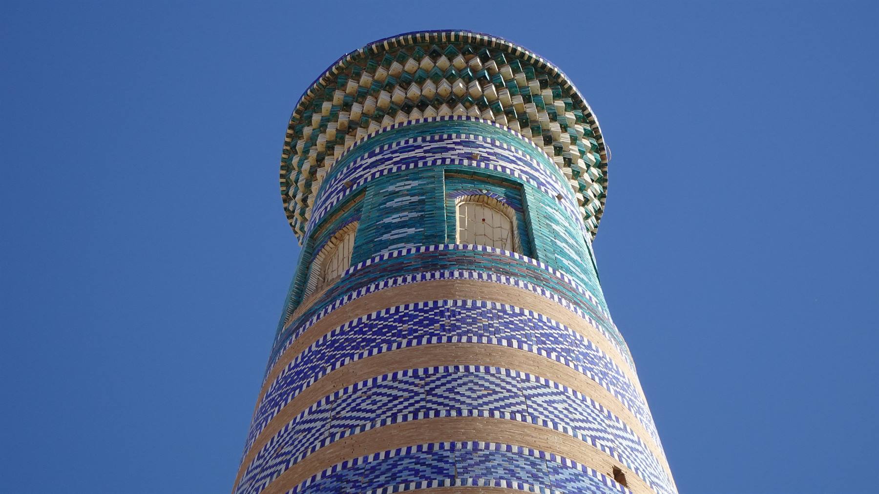Il minareto di Khiva con maioliche blu e verdi contro il cielo