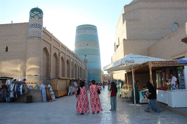 Donne in abiti tradizionali camminano davanti al minareto Kalta Minor a Khiva