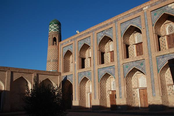 Madrasa in mattoni con maioliche blu e minaretto verde a Khiva